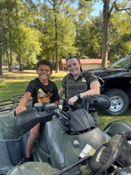 LDWF female enforcement agent smiling with a young boy showing him an LDWF ATV