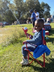 Young boy smiling with a fishing pole casting a line at Waddill Wildlife Refuge 