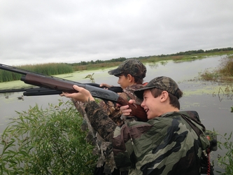 Two young boy duck hunters aiming their guns at ducks at White Lake Wetlands Conservation Area 