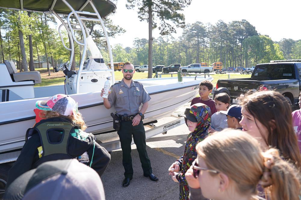 students listening to an LDWF agent in front of a boat