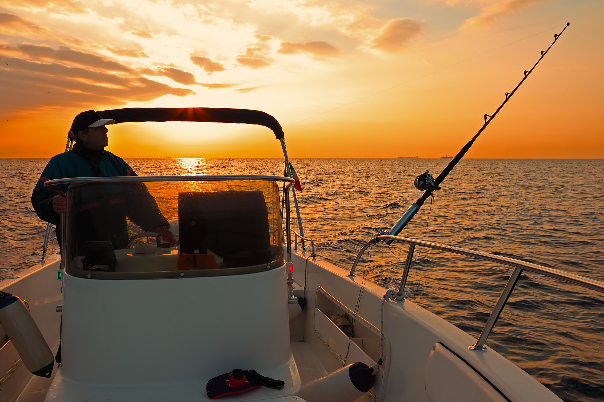 Man fishing on a boat a sunset
