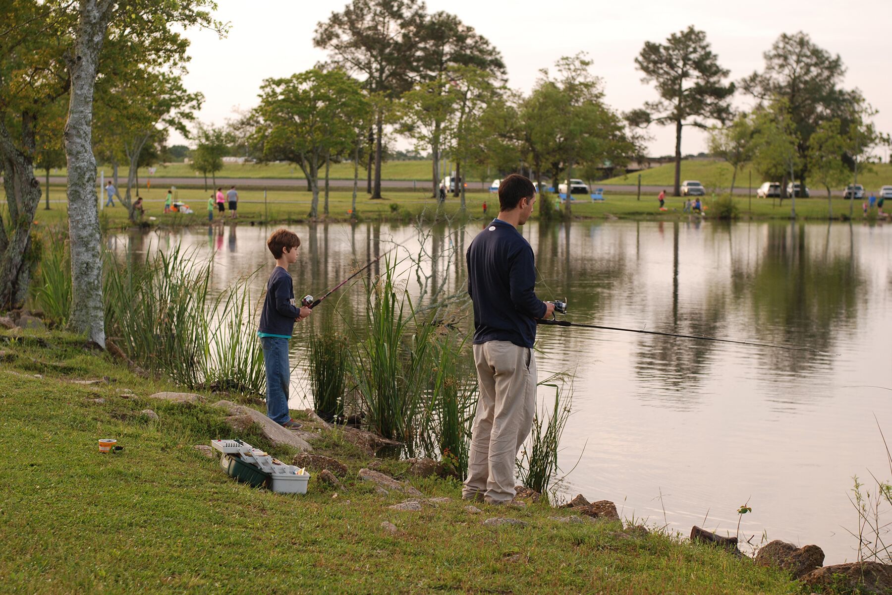 father and son fishing on the edge of a pond