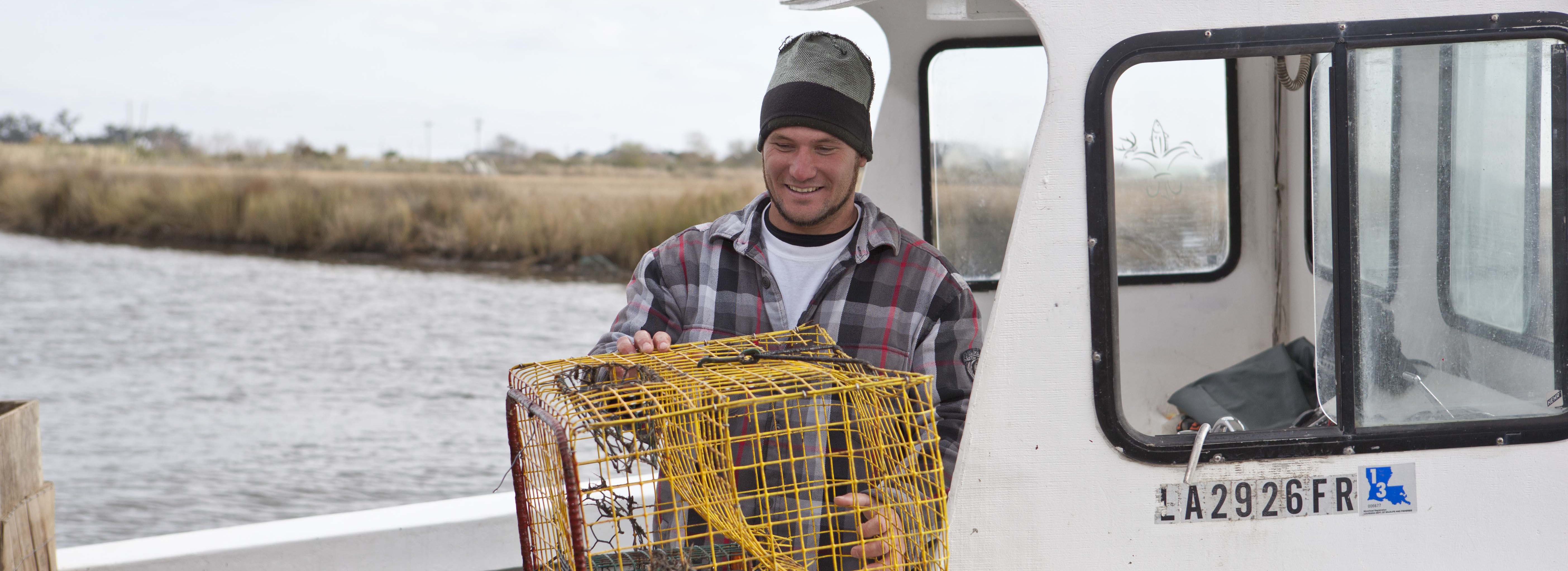 commercial fisherman on a boat holding a crab trap