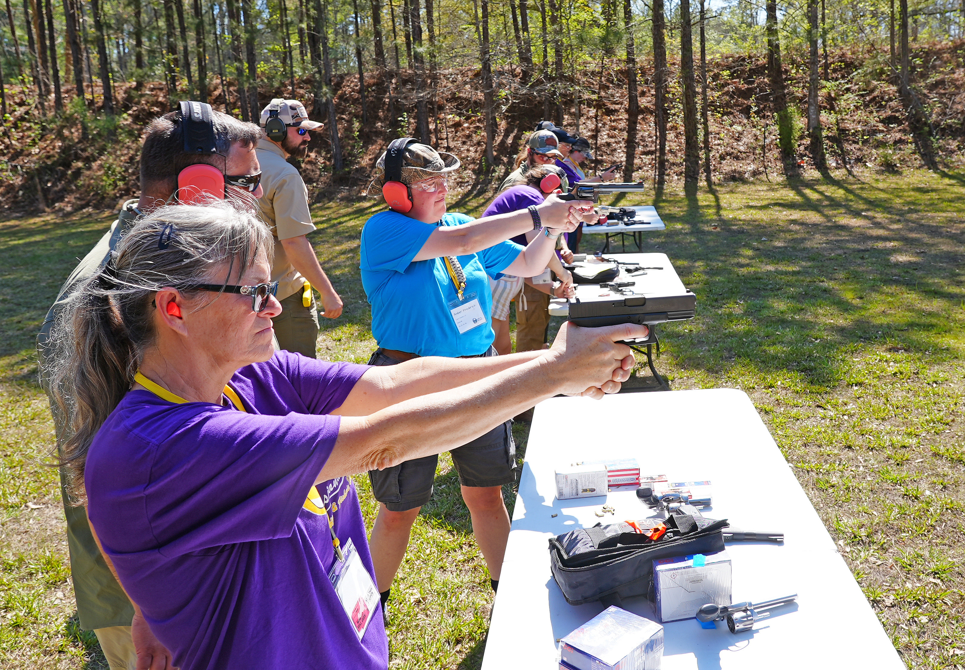 Participants practice shooting hand guns in a shooting range in a firearms fundamentals class